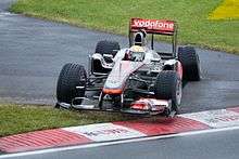 Lewis Hamilton driving a McLaren Formula One car with a damaged left rear tyre