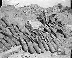 A picture taken in 1918 showing two men of the 9th Battalion, Royal Sussex Regiment sit beside a dump of 6 inch Mortar bombs.