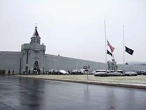wall of building with text that says Attica Correctional Facility.  Flags are visible outside at half-staff.