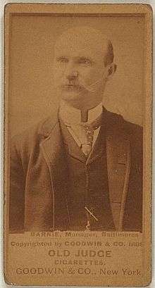 Baseball card showing a bald, white man with a mustache in a medium shot. The man is wearing a suit and tie. The first line of the caption beneath the photo says "BARNIE, Manager, Baltimore". Beneath that the caption says "OLD JUDGE CIGARETTES" and "GOODWIN & CO., New York".