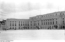 Large public building fronted by sentry boxes and a near-empty square.