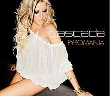 A portrait in the background colour of black featuring the front profile of a blonde woman. The woman is sitting down looking down to her left side wearing a low-cut white strapless dress. To the right of her in large, white, capital letter font is the name 'Cascada' and directly below it in the same font but in an orange colour is the title 'Pyromania'.