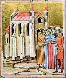 A crowned man and a man wearing a hat shake hands before a priest at a church