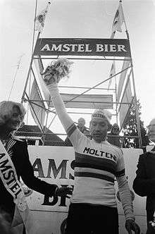 A picture of a cyclist holding flowers.