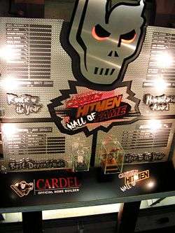 A large silver, metal display hanging high on a wall. It features winners of four awards and miniature replicas of two trophies.