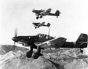 a black and white photograph of aircraft flying with a mountainous backdrop