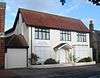 A converted house whose downstairs windows and entrance door are covered with white-painted panels. The three upper-storey windows are glazed and have brown frames. An entrance porch is carried on spindly columns.