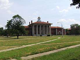 Photograph of the grand main building at St. Elizabeth's Hospital, with pillars and cupola, across a grassy lawn.