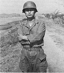 An Asian man in a military uniform in an outdoor setting