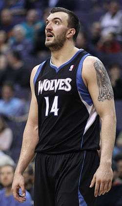 Nikola Peković, bearded, in a black Timberwolves jersey with blue and white trim