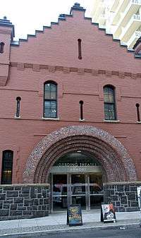 Two story brick building opening onto the sidewalk. Entrance is set in rounded arches.