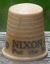 An off-white thimble, with the visible black lettering, "NIXON/Put the ne ...