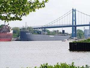 Gray barge sailing under a bridge