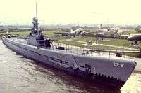 Photograph of the bow of the USS Drum, mounted on concrete supports on land as a museum ship.